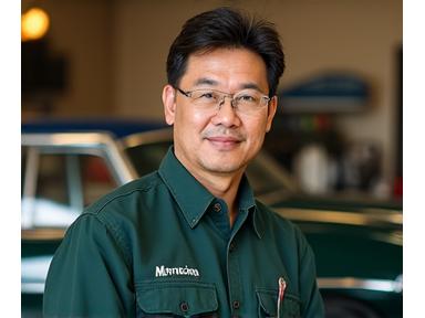 Portrait of David Goh, Classic Car Restoration Expert, with a vintage vehicle in the background.